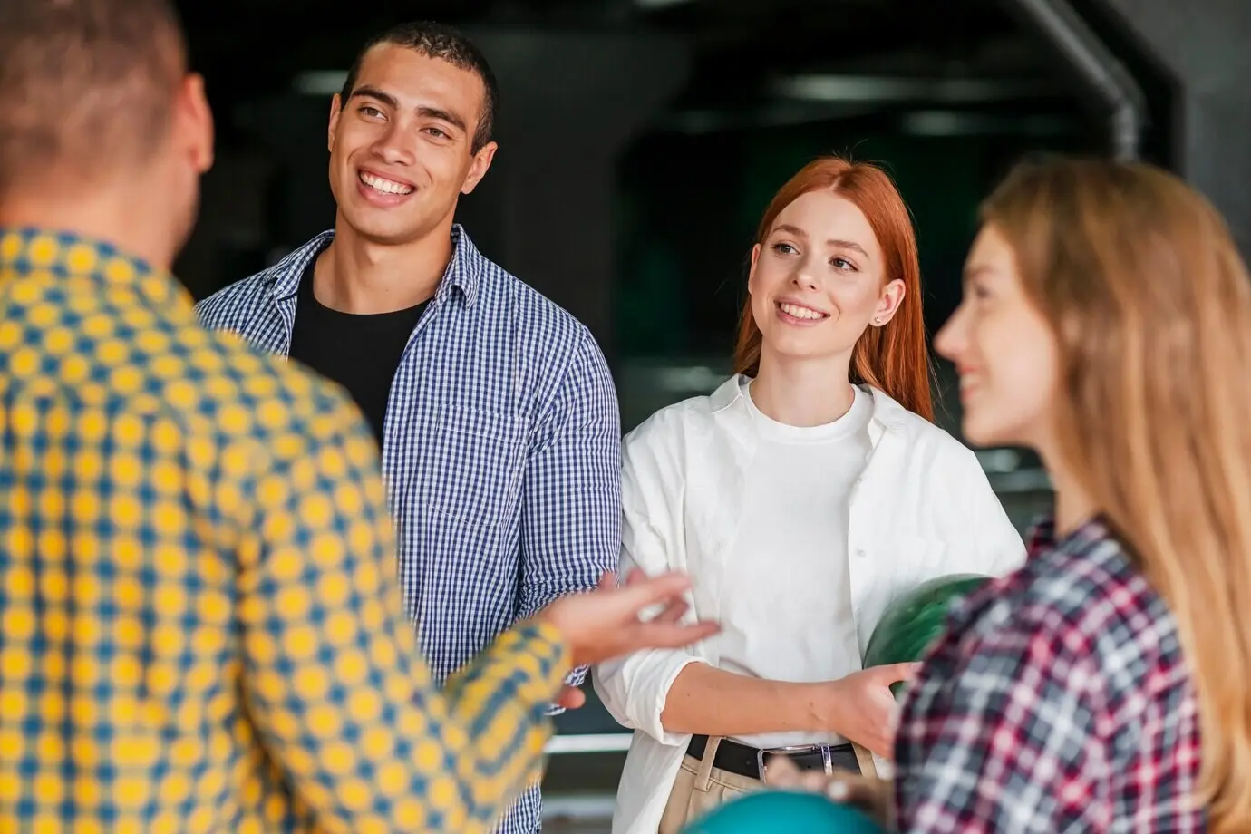 Улыбающиеся друзья стоят в боулинг-клубе.