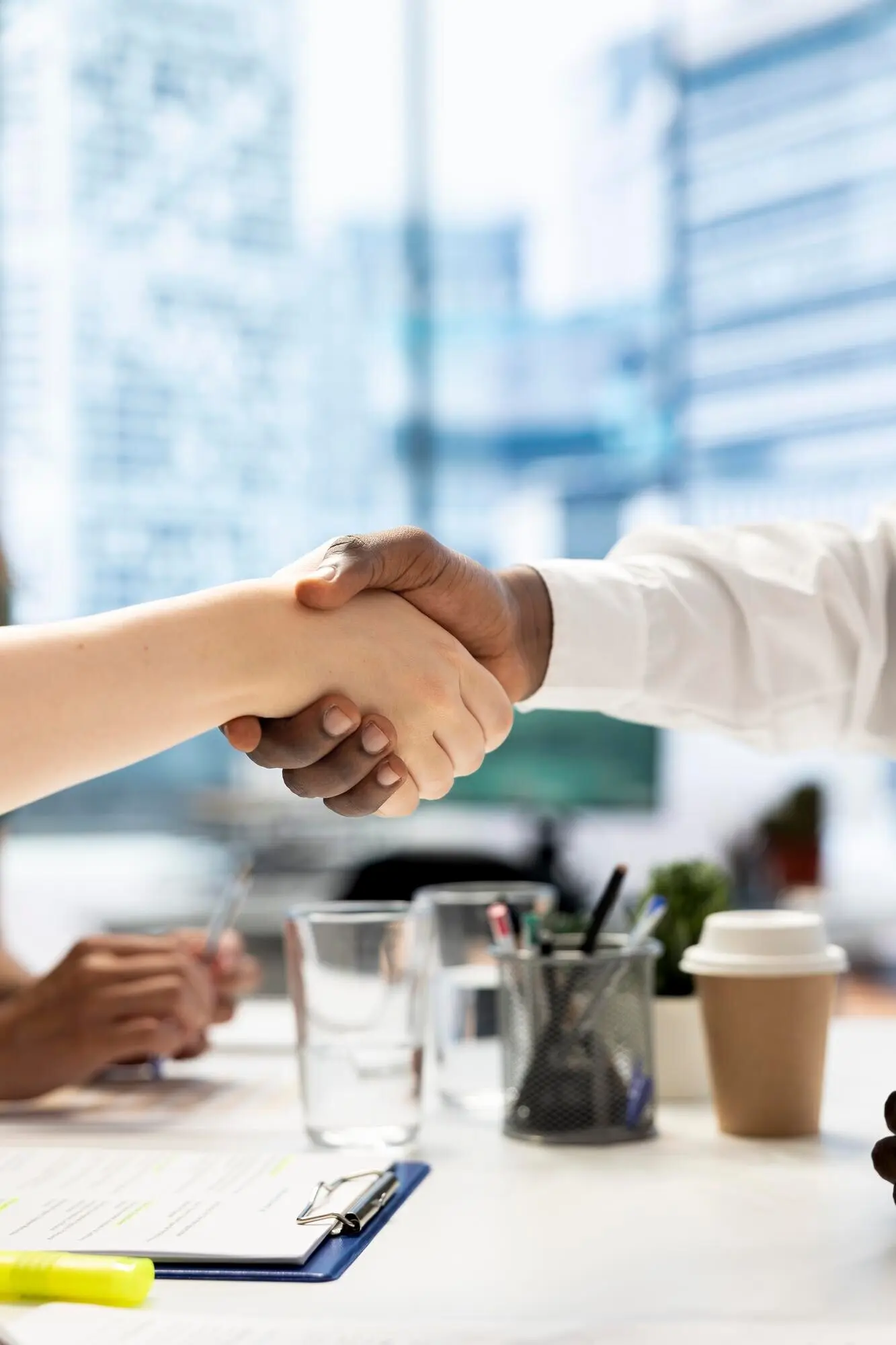 Деловые люди на встрече приветствуют друг друга рукопожатием в офисном рабочем пространстве.